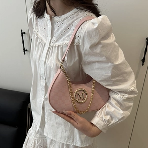 Pink crescent underarm bag with gold M buckle worn with a white lace shirt