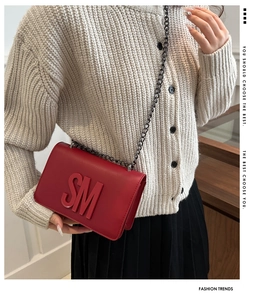 Close-up of bright red leather flap bag with 3D SM letter logo and dark metal chain