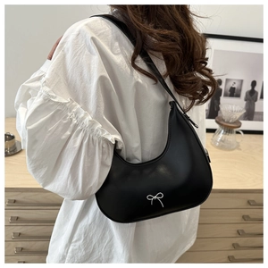 Détail du sac croissant noir avec nœud argenté et texture en cuir de qualité