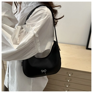 Detail shot of black half-moon hobo bag with a silver metallic bow and sleek zipper