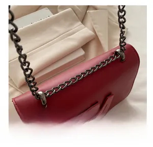 Detail shot of the red faux leather shoulder bag with bold metal M letter and chunky chain