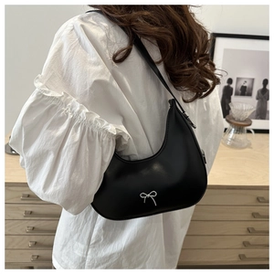 Detail view of a black hobo bag with a silver metal bow and premium matte leather texture