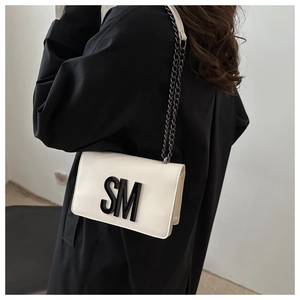 Model wearing a white leather crossbody square bag with black SM letter and chain strap