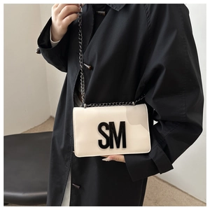 Detailed view of the large 3D black SM logo on creamy white leather crossbody bag