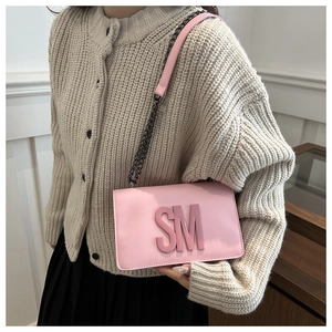 Close-up of pink crossbody bag with 3D SM letter logo and dark metal chain strap