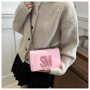 Detail of pink chain shoulder bag featuring 3D letter decoration and faux leather texture