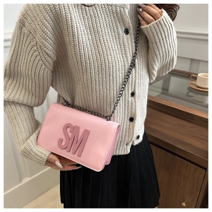 Detail shot of a pink chain shoulder bag with 3D SM letter decoration on casual model outfit