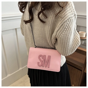 Pink crossbody bag with 3D SM letters and black chain strap styled with casual outfit