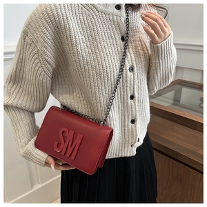 Detailed view of red leather crossbody bag with SM embossed letters and metal chain strap
