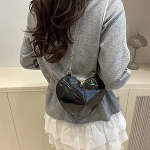 Black holographic heart crossbody bag with gold chain strap shown on model profile view