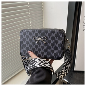 Detail of crossbody bag with M-letter print and stylish wide woven shoulder strap