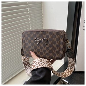 Close-up of vintage monogram pattern with silver bow charm on a stylish crossbody bag
