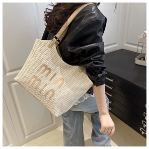 Detail of hand-woven beige tote with min min embroidery and brown leather shoulder straps