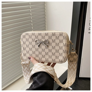Detailed view of cream crossbody bag with M-pattern print and wide geometric strap