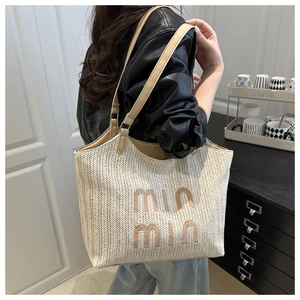 Detailed close-up of woven tote bag texture with min min lettering and leather straps
