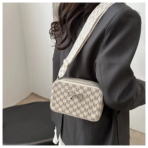 Model wearing a vintage beige crossbody bag with M-pattern print and wide woven strap