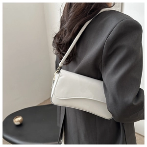 Close-up of white minimalist baguette bag on model wearing a dark grey suit jacket