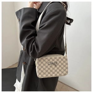 Side view of beige crossbody bag with monogram pattern and metal bow accent on model