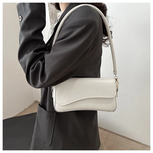 Detail view of cream white baguette bag with asymmetric flap worn by model