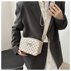 Detail of crossbody camera bag with letter pattern and wide woven shoulder strap