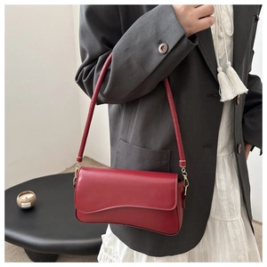 Detail view of red leather baguette bag with gold metal buckles on a model