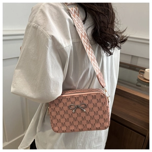 Detail of pink crossbody bag with M-letter print and wide geometric strap