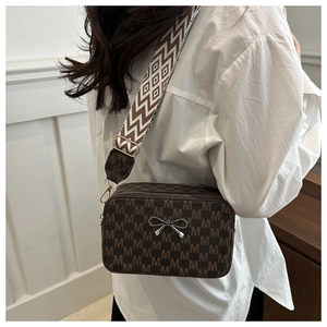 Detail view of brown crossbody bag with M-pattern and geometric wide shoulder strap