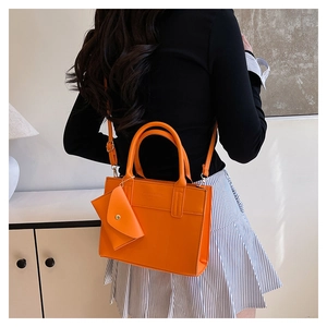 Orange leather tote bag with matching coin purse and adjustable shoulder strap worn by model