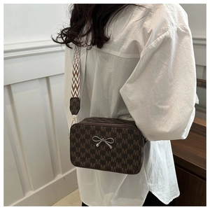 Close-up of vintage brown bag with M-pattern, silver bow buckle and geometric strap