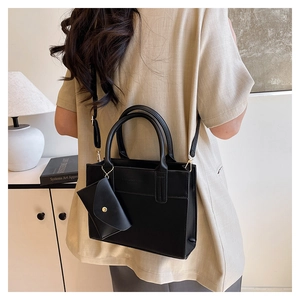 Detail of black faux leather tote bag with round handles and decorative small coin purse