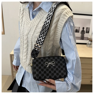 Detailed view of black monogram crossbody bag with wide geometric woven shoulder strap