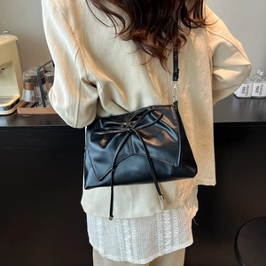 Large black PU leather tote bag with a decorative bow shown on model in a cafe