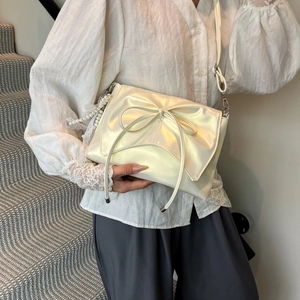 Chic cream bow shoulder bag with pearl lace charm for women worn on a white staircase