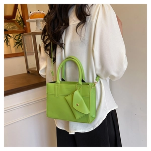 Green PU leather crossbody bag with matching coin purse charm shown in cozy interior