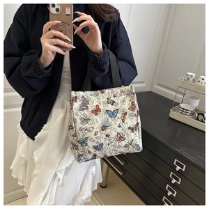Detail of colorful butterfly tapestry tote bag held by a model in a minimal setting
