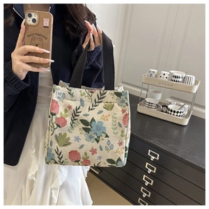 Close-up of knit canvas tote bag showing floral patterns and woven texture in a home setting