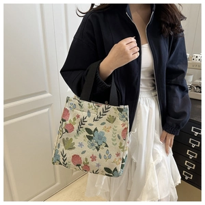 Detail view of vintage oil painting style canvas tote bag with floral embroidery worn by a model