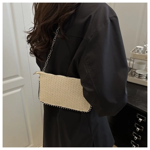 Dettaglio della trama intrecciata beige con rivetti argentati e catena in metallo