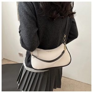 Detail of off-white crescent underarm bag with black contrast piping and gold hardware