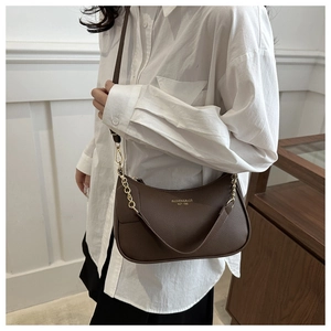Detail of dark brown lychee leather underarm bag with gold logo and metal chain