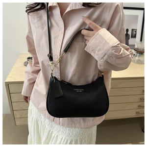 Detail of black crescent shoulder bag featuring lychee texture and gold chain strap decoration
