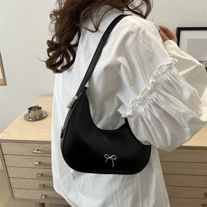 Sac hobo noir chic avec nœud argenté porté à l'épaule pour un style moderne élégant