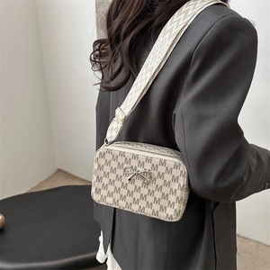 Retro monogram crossbody bag with bow hardware and wide strap worn by model