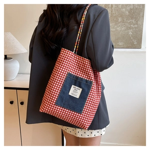 Detail of red checkered canvas tote bag with denim pocket and woven shoulder strap