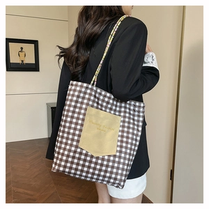 Détail du sac cabas en toile à carreaux avec poche contrastée et bandoulière tressée