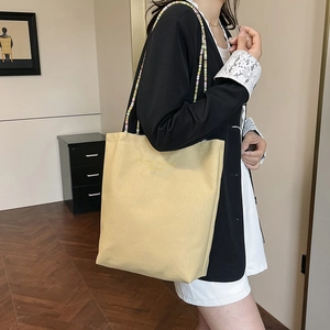 Canvas tote bag with colorful beaded straps and Dreaming Fashion text in yellow