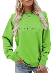 Détail du sweat vert néon à col rond avec lettrage Skin Therapist noir et poignets côtelés