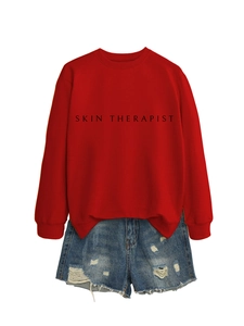 Détail du sweat rouge Skin Therapist assorti à un short en jean bleu délavé