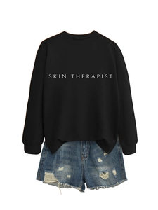 Vue à plat d'un sweat-shirt noir imprimé Skin Therapist avec un short en jean déchiré
