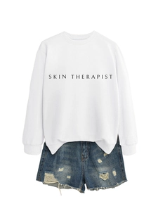 Détail du sweat-shirt blanc avec imprimé Skin Therapist et mini-short en jean usé